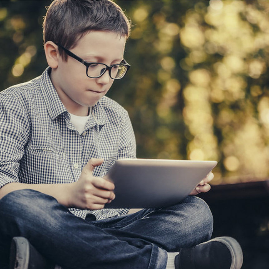 A boy with glasses looking at a iPad