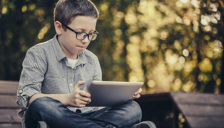 A boy with glasses looking at a iPad